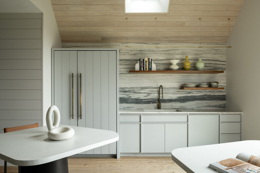 Beautiful custom design cabinetry in a light gray blue color. Nickel gap paneling look for appliance fronts. Custom designed integrated pulls in both painted and clear finish.  Walnut floating shelves supported on concealed brackets. Pantry of this project was a walnut variant of this design.