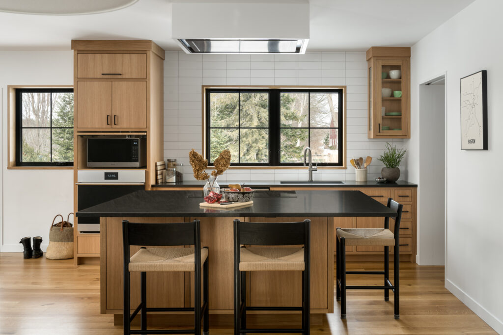 Custom design cabinetry in a modern kitchen with light wood and black drawer pulls.