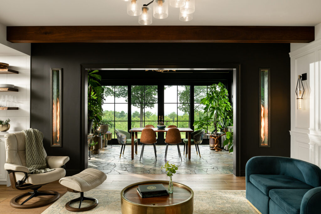 Interior design considerations go into this interior space. Neutral tones in the furniture and wall are brought to life by the natural light coming through floor to ceiling panel windows overlooking a lush green countryside. An open concept space is decorated with indoor plants for a lived-in feel