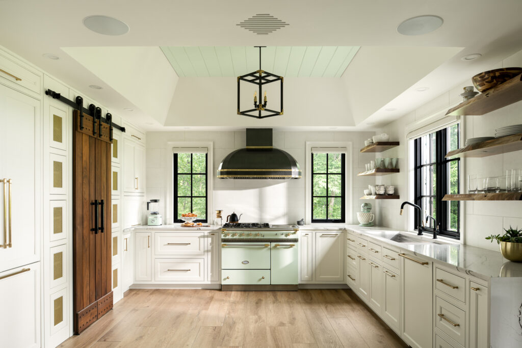 Modern farmhouse kitchen renovation with barn doors to pantry, white and seafoam green appliances with gold and black accents built by Silver Maple. A final project photo to highlight construction details and natural lighting.