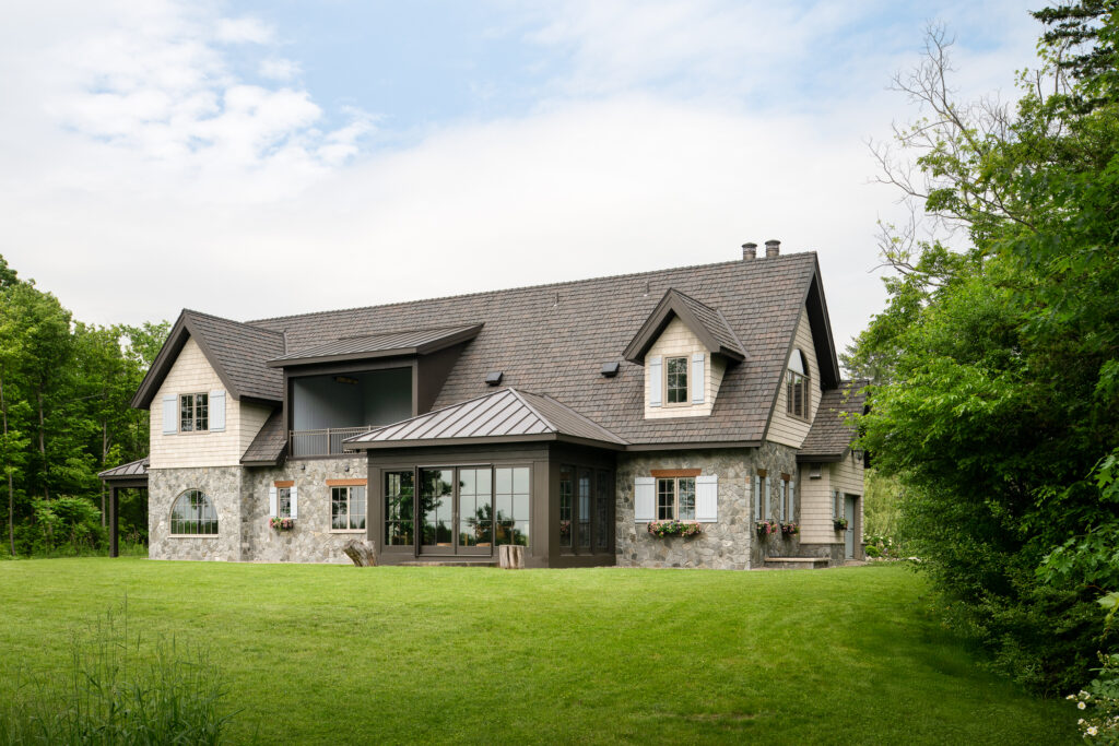 The hero image of a whimsical modern stone custom home built by Silver Maple in Vermont.