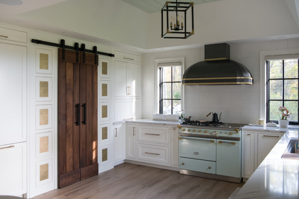 Modern farmhouse kitchen renovation with barn doors to pantry, white and seafoam green appliances with gold and black accents built by Silver Maple. A behind the scenes scouting image. 