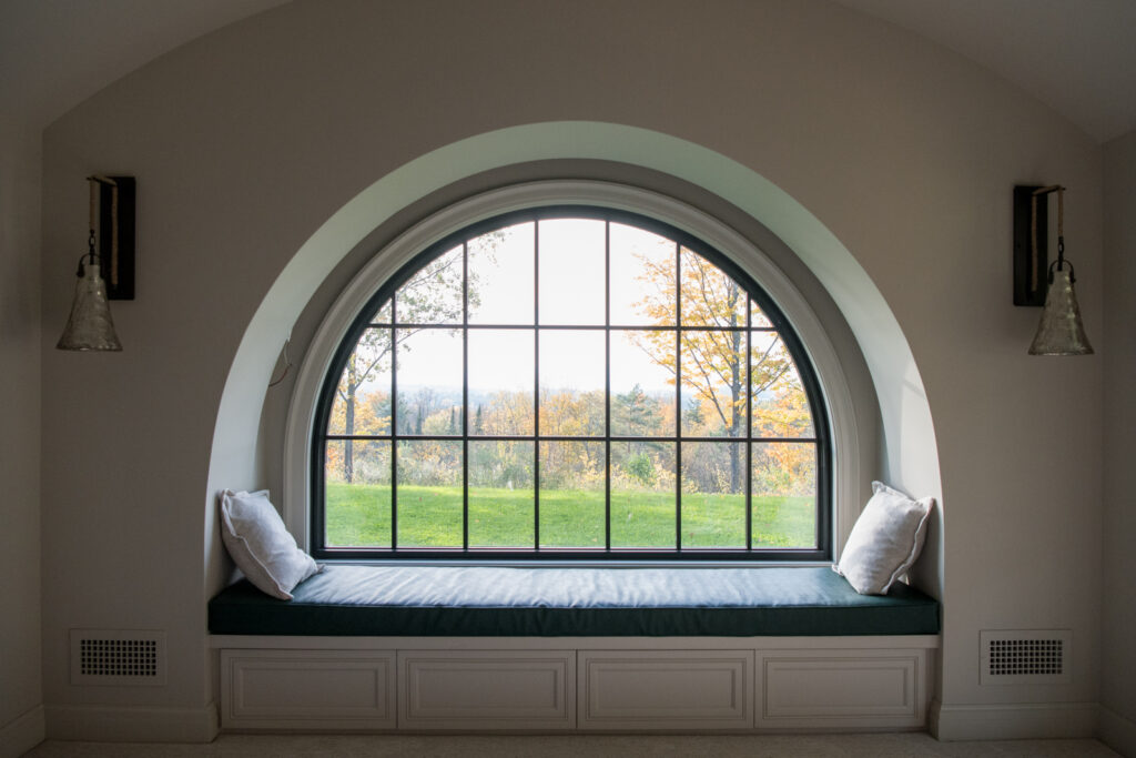 A custom built-in nook underneath an arched window looking outside on a fall day in Vermont