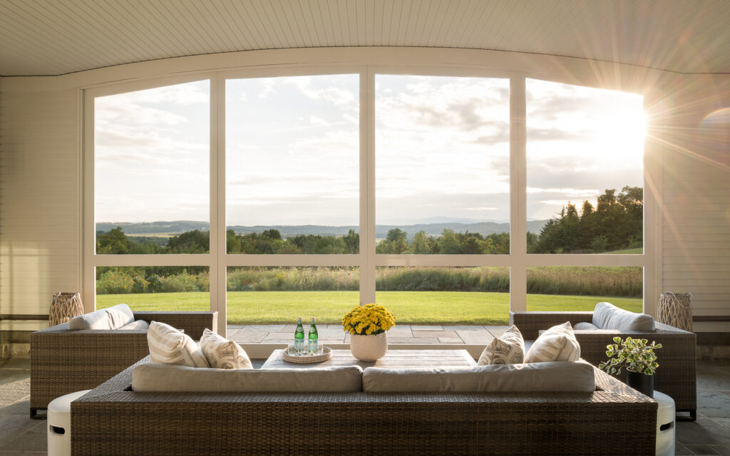 A three-season room looking out to a mountainous Vermont landscape through floor to ceiling windows letting in natural light for a healthy home.