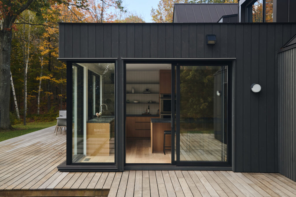 A modern renovation on a panelized home from the outdoor wooden deck looking inside through sliding glass doors to a newly renovated kitchen built by Silver Maple