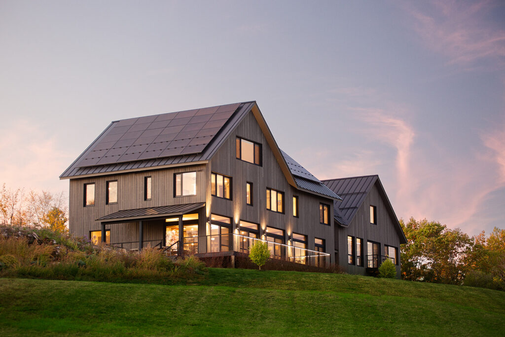 The exterior of a panelized healthy home at sunset. Interior lighting casting a soft glow against the sky during blue hour